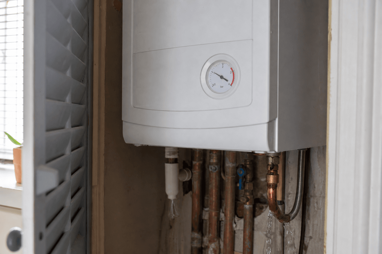 Boiler pressure gauge above 3 bar with drip from pressure-relief valve in UK airing cupboard