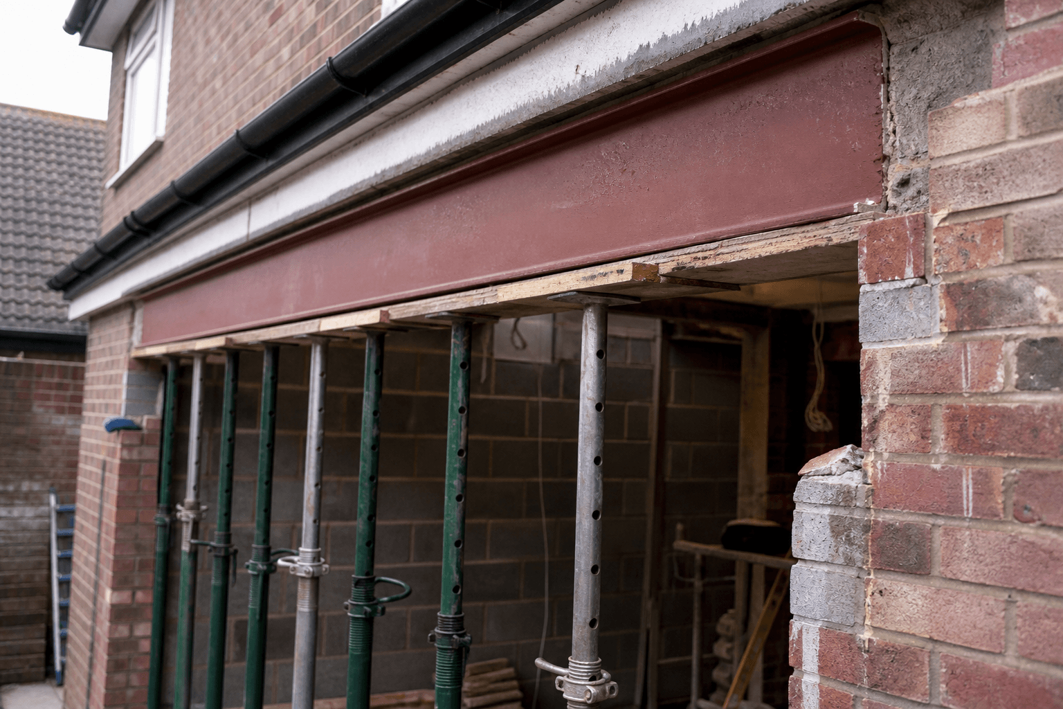 Close-up of a steel RSJ being lifted into a brick wall opening on a UK extension