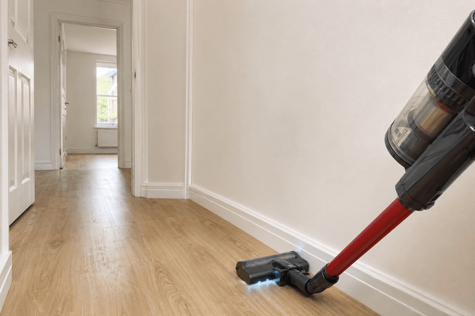 Vacuuming along skirting in a freshly finished UK hallway [dedupe:taskino:blog:post-build-clean-home-reset-maintenance:inline-3]
