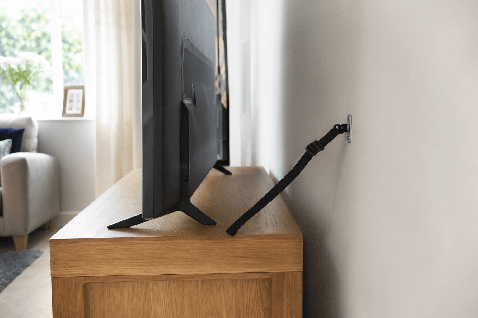 Large TV on stand with anti-tip strap for child-safe UK home setup [dedupe:taskino:blog:is-wall-mounting-a-tv-worth-it-long-term:inline-2]