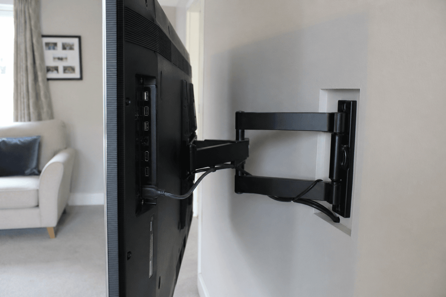 Articulating TV wall bracket pulled out showing tidy cable access [dedupe:taskino:blog:is-wall-mounting-a-tv-worth-it-long-term:inline-3]