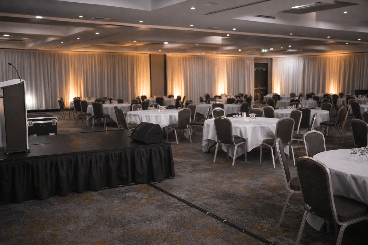Prepared ballroom tables and drape uplighting for a small UK event [dedupe:taskino:service:event-setup:banner]