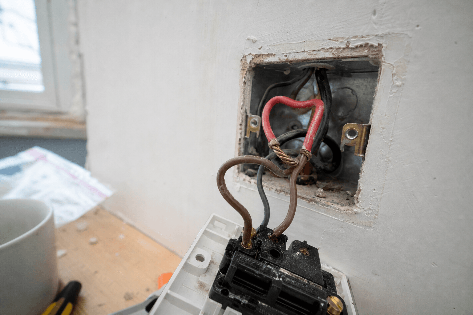 UK light switch backbox showing mixed old red and new brown conductors without sleeving
