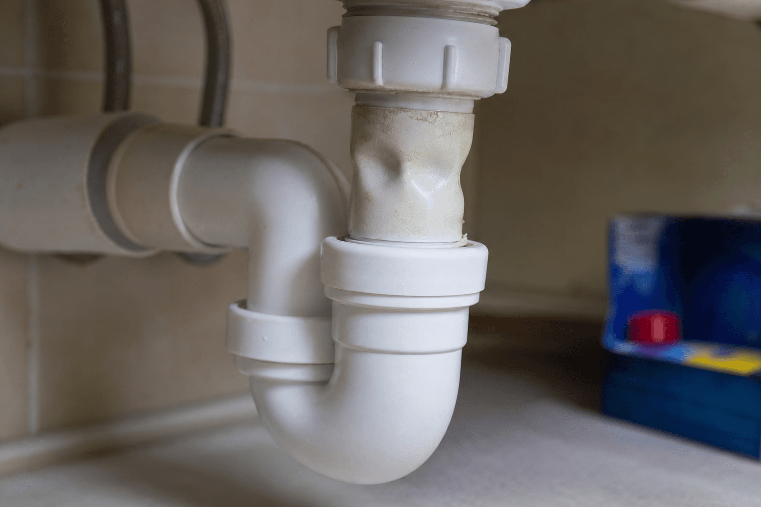 White UPVC bathroom waste pipe under a basin with drain cleaner nearby