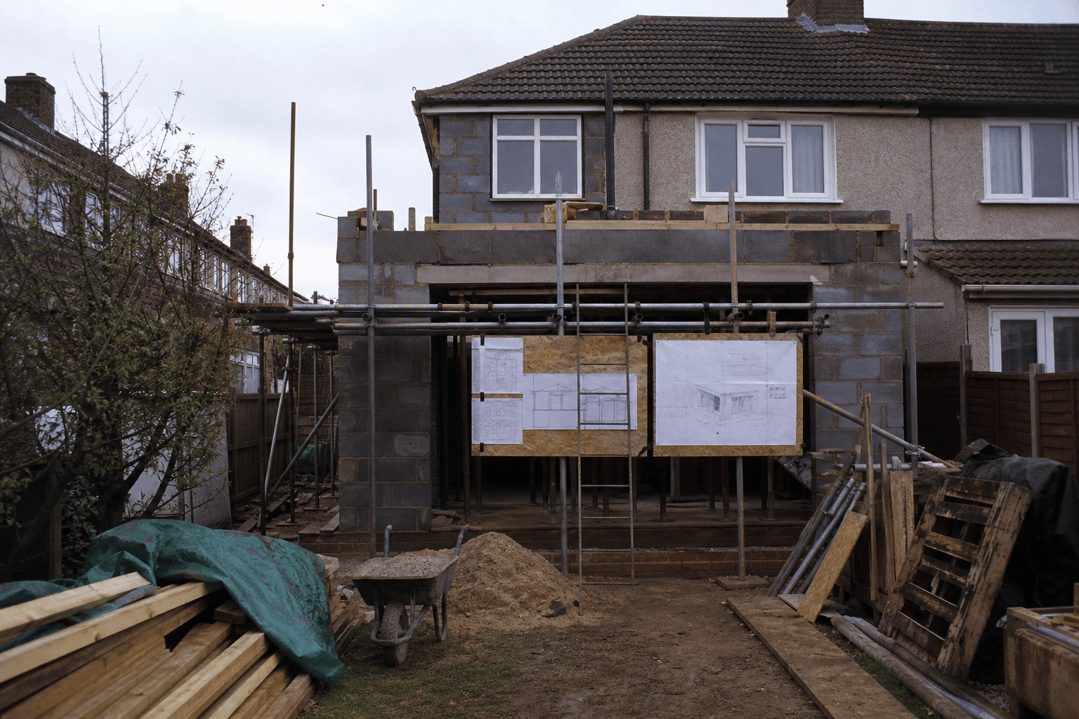 Rear extension build on a UK semi with scaffolding and pinned architectural drawings