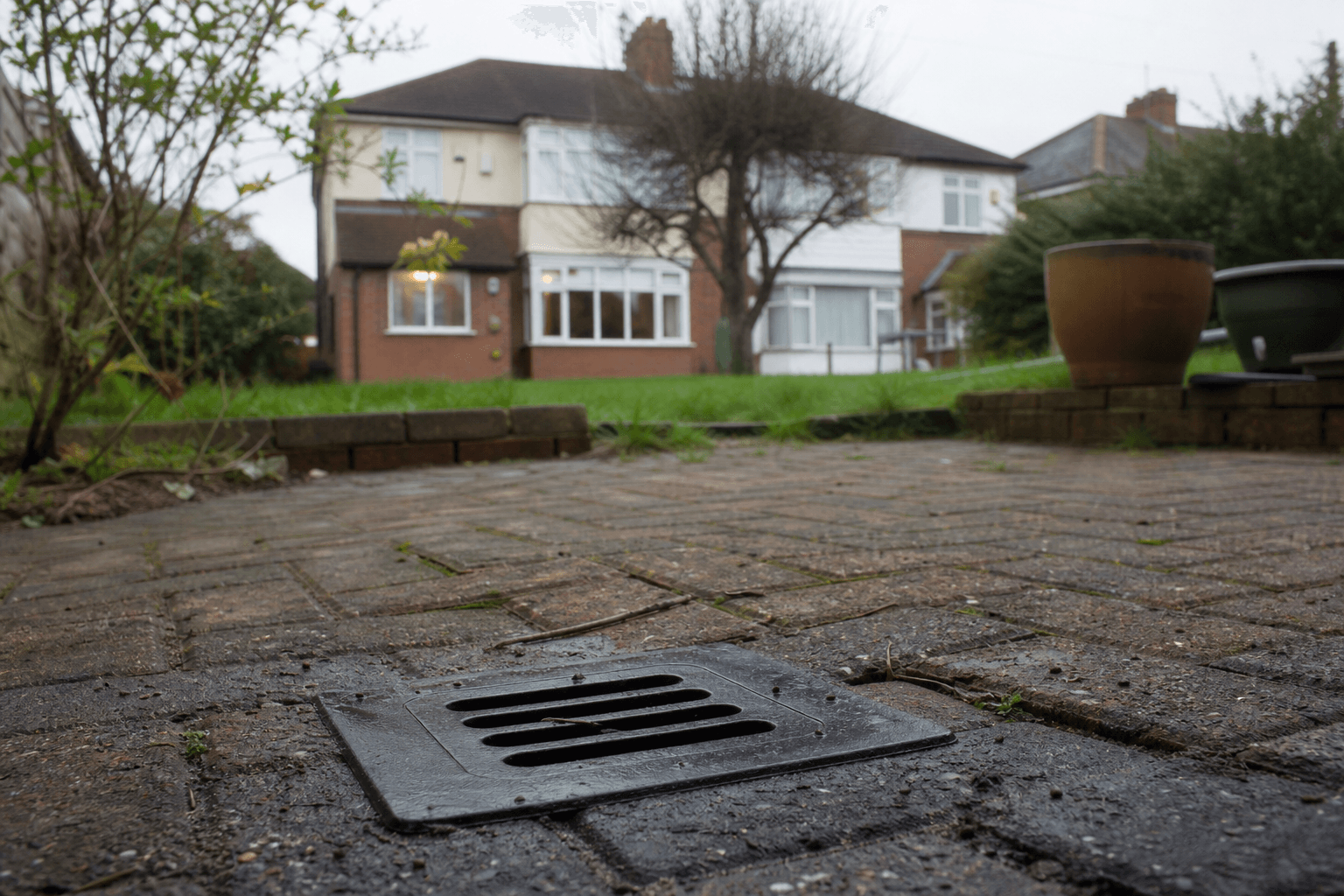 UK back garden drain gully on a patio, cover for a blocked drain comparison article hero