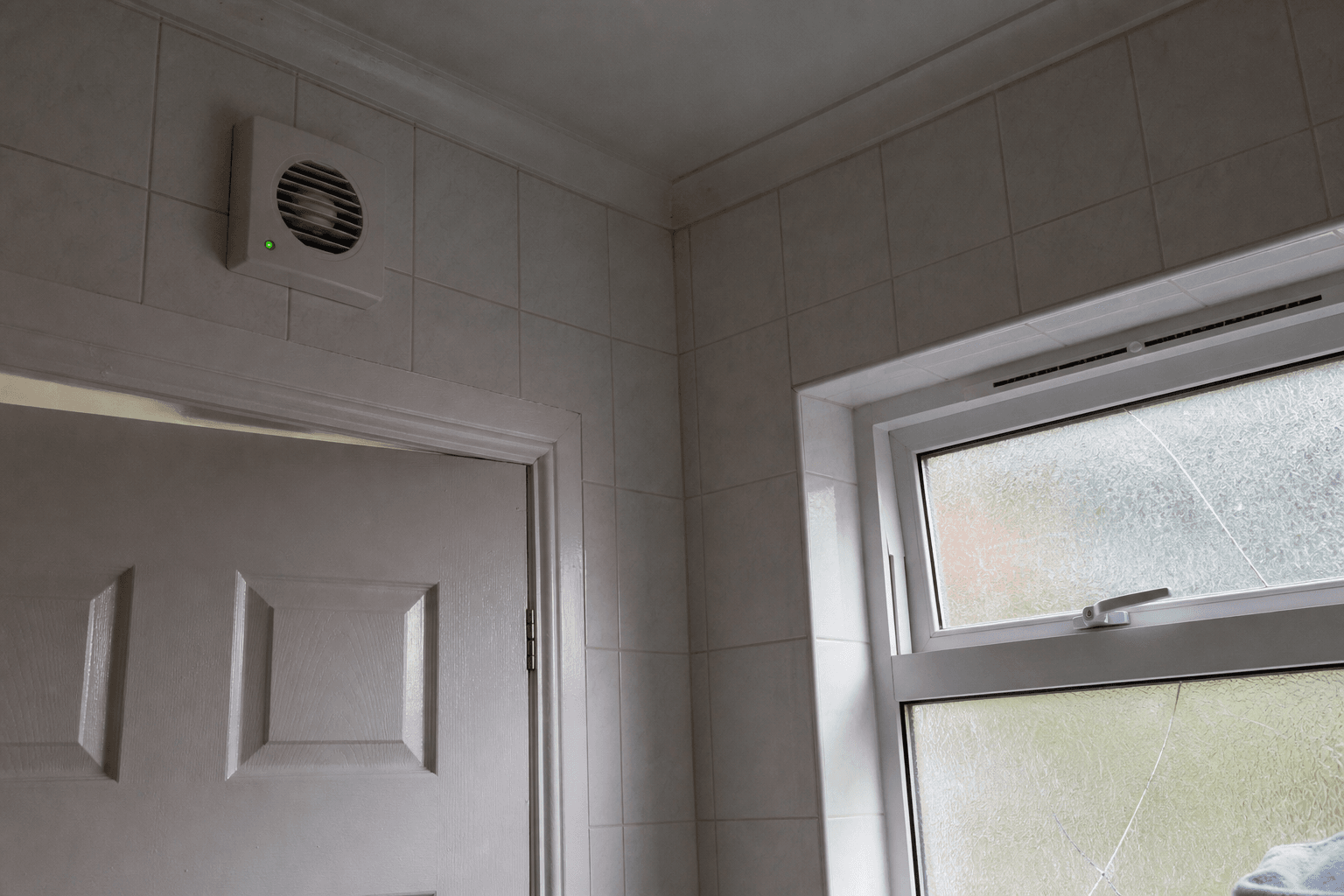 UK bathroom extractor fan above door with trickle vent and daylight