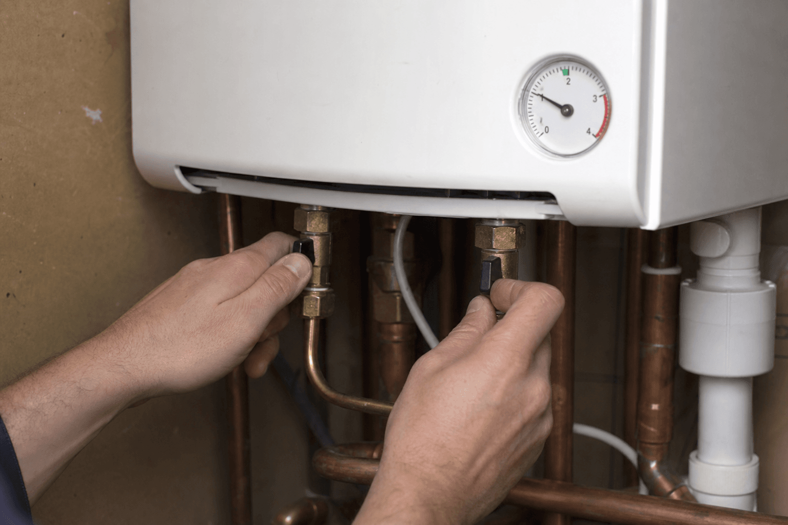 Hands topping up UK combi boiler pressure via the filling loop