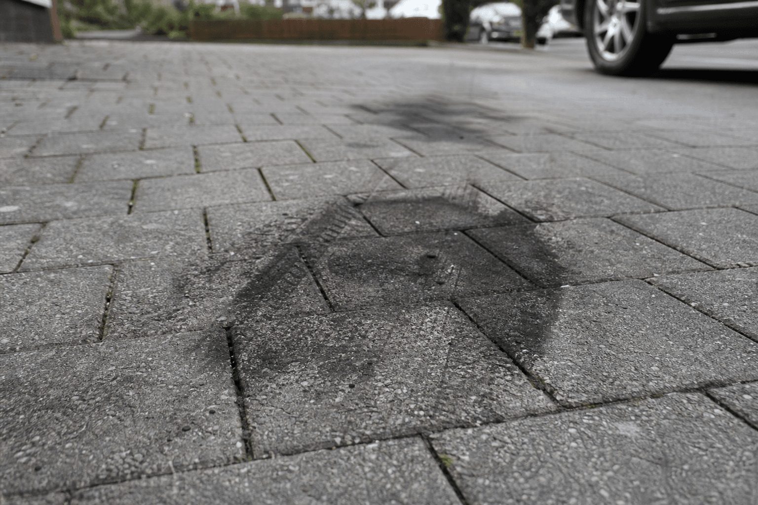 Dark oil stain on grey block paving driveway blocks