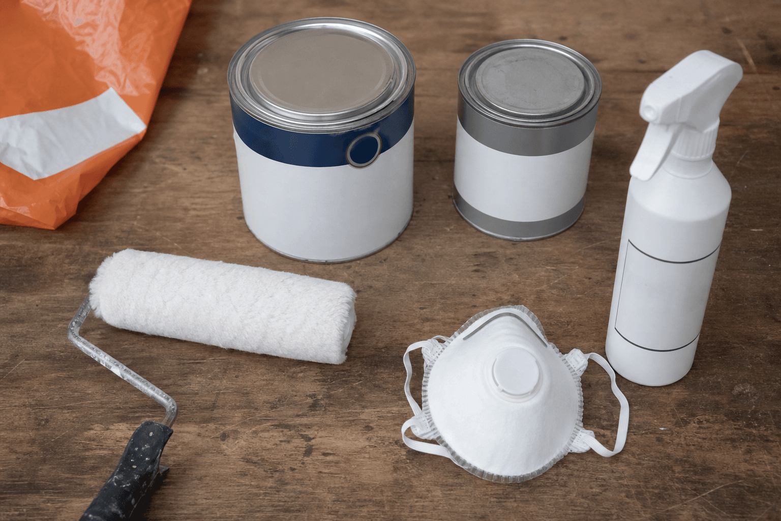 Flat lay of anti-mould paint tins, mould spray and roller on a workbench