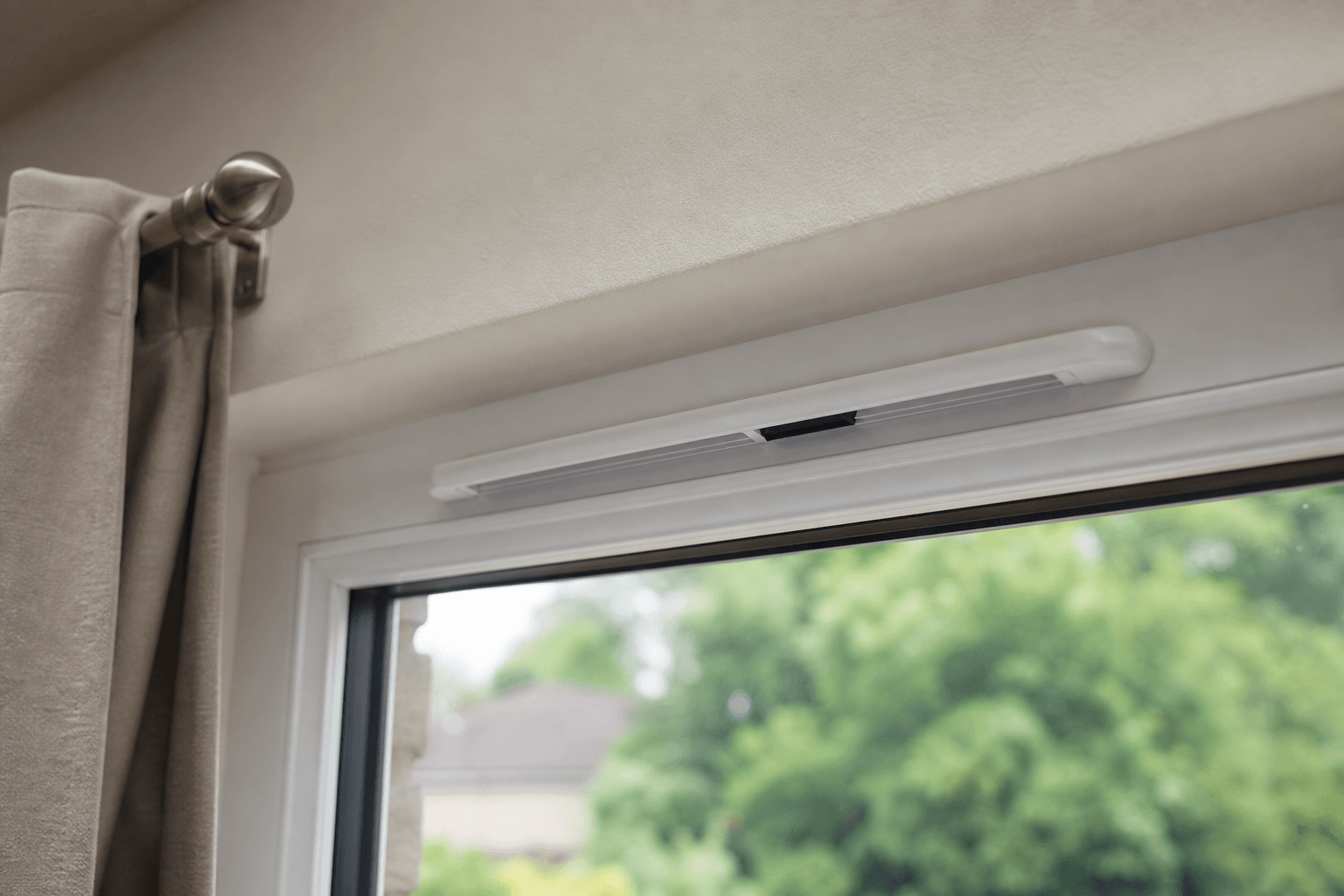 Open trickle vent on a white uPVC window frame